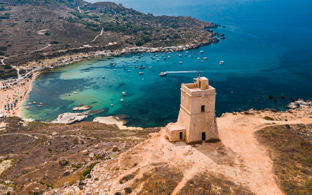 The Ghajn Tuffieha Tower overlooks the sweeping curve of golden-red sand of Gnejna Bay, one of the many incredible beaches on offer in Malta