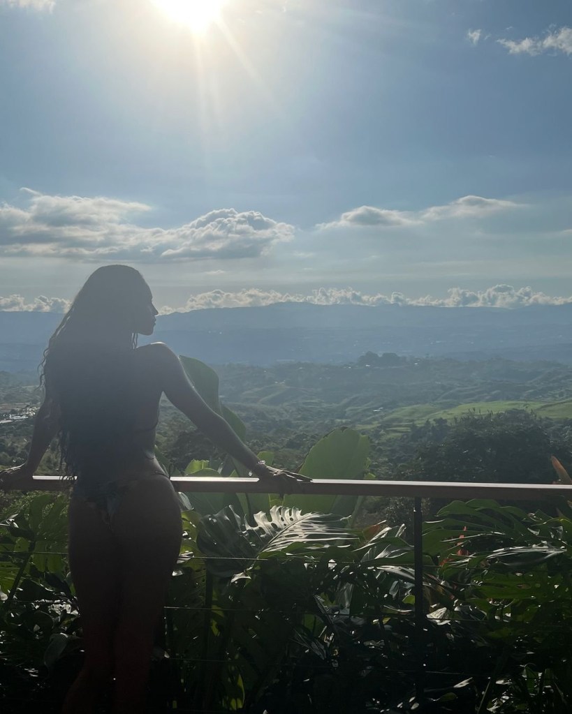 Vick Hope standing on a balcony overlooking a jungle