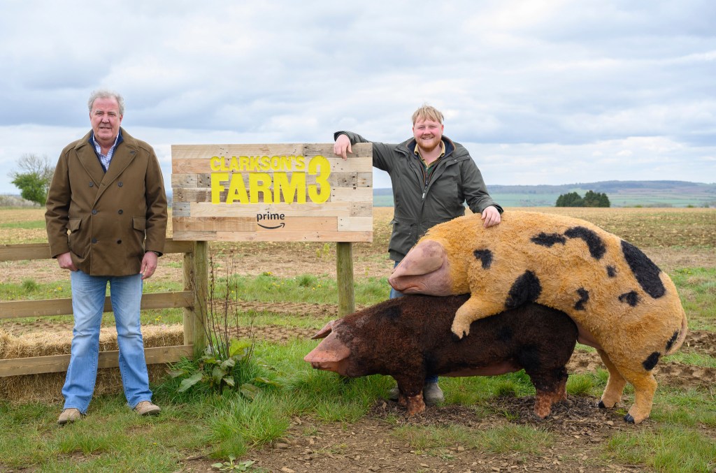Jeremy Clarkson and Kaleb Cooper smiling next to replica pigs