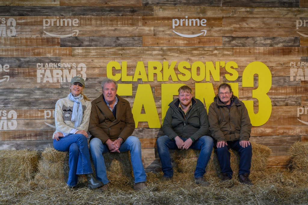 Jeremy Clarkson, Lisa, Kaleb and Gerald all smiling while sitting on hay bales