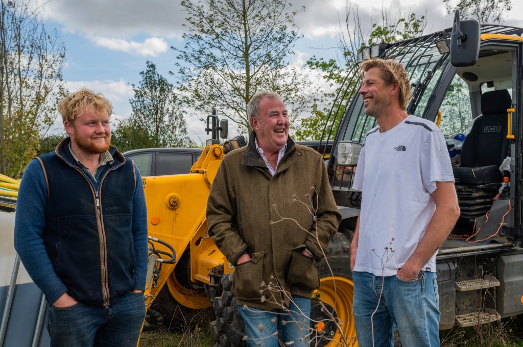 Kaleb Cooper, Jeremy Clarkson and Andy Cato laughing together in front of a tractor 