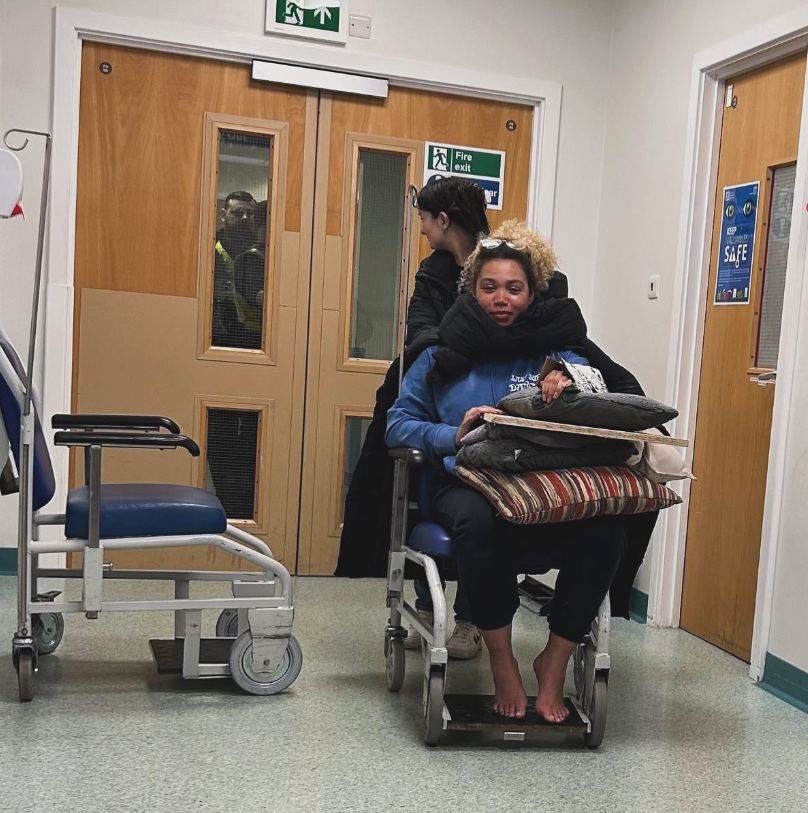 Ruby Barker being wheeled through a hospital corridoor