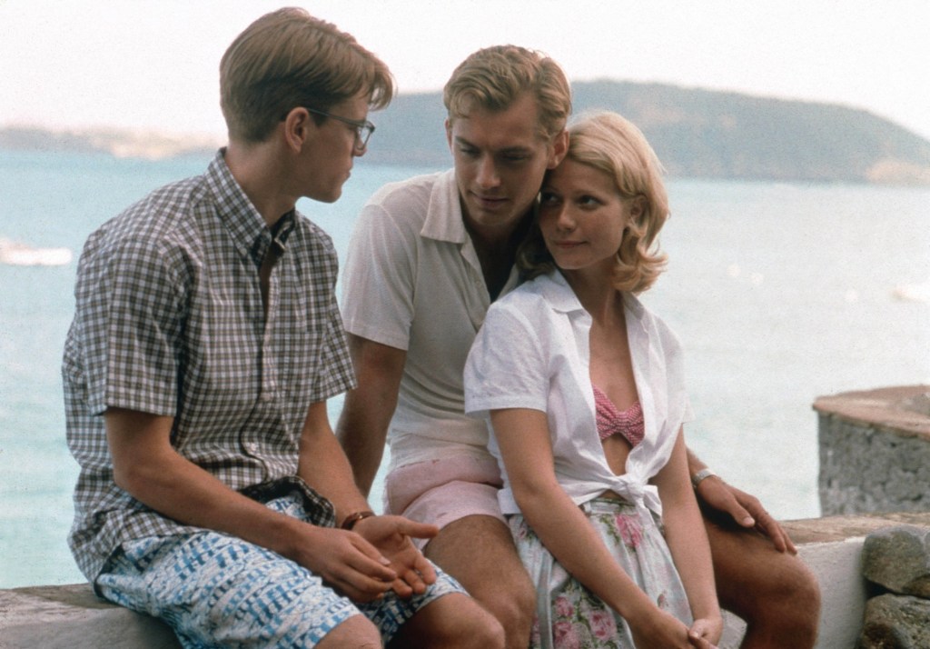 Gwyneth Paltrow, Matt Damon and Jude Law sitting on a wall with the sea behind them in The Talented Mr Ripley