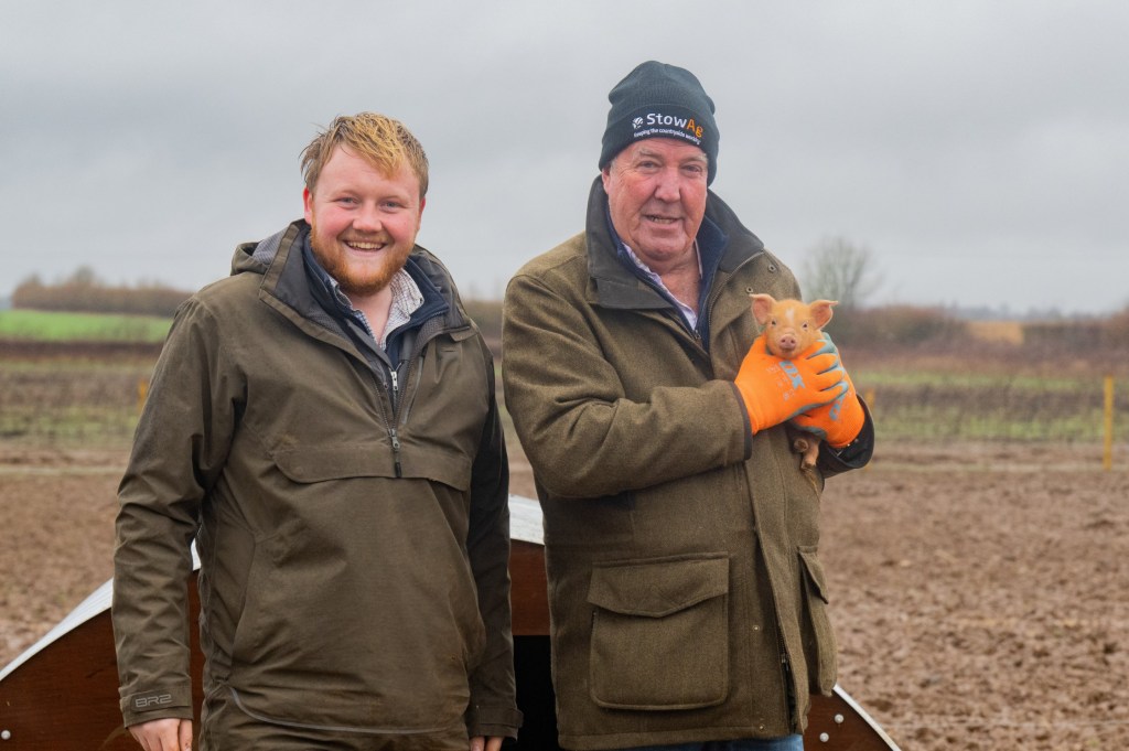 Jeremy Clarkson and Kaleb Cooper with a piglet on Clarkson's Farm