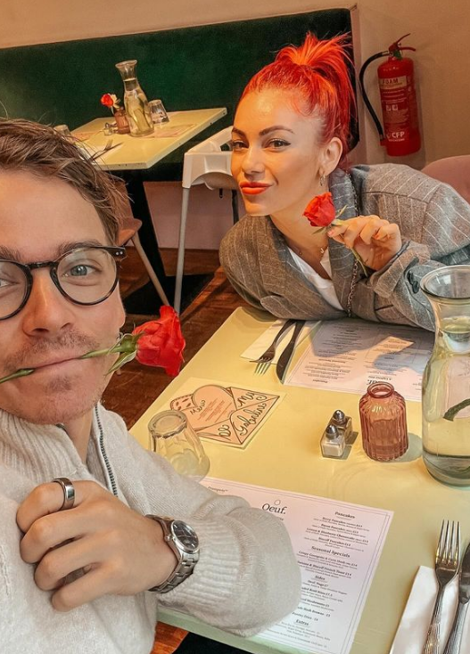 Joe Sugg and Dianne Buswell holding roses at a restaurant 
